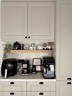 a kitchen with white cupboards and appliances on the counter top, including coffee maker