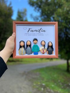 a person holding up a family figurine in front of a road with trees