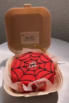 a spider - man cake in a plastic container with writing on it