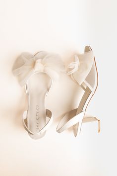 a pair of white high heeled shoes with a bow