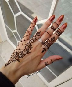 a woman's hand with hennap tattoos on her fingers and wrist,