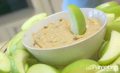 an apple and peanut butter dip in a bowl on top of sliced apples with a spoon