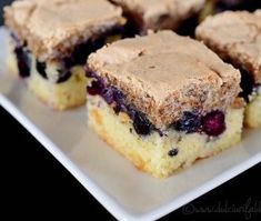 several pieces of blueberry coffee cake are on a white plate with black tablecloth