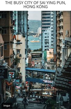 a city street filled with lots of tall buildings next to the ocean in hong kong