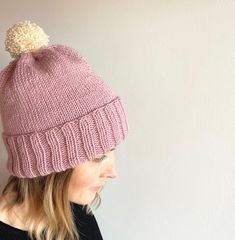 a woman wearing a pink hat with a white pom - pom