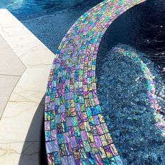 a pool with a colorful mosaic design on the edge and water running down it's side