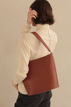 A timeless shape for the everyday. The Mia and Mini Mia Bucket Bags are our take on the iconic shape that is not only chic but also loaded with function. The bags are lightweight with a top zipper closure (we thought you would appreciate that :) and a rear roomy pocket for easy phone access. Available in rich jewel-tone hues (and of course our go-to neutrals) ready to be worn between seasons and beyond. Details 12.5" L x 10.75" H x 6" D Gold hardware YKK exterior zipper Fully lined in signature Bucket Bags, 6 D, Jewel Tones, Gold Hardware, Bucket Bag, Sale Items, Vegan Leather, Walnut, Exterior