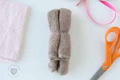 a pair of scissors and some towels on a white table with pink ribbon next to it