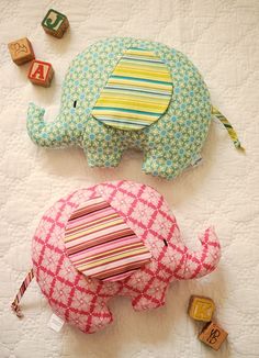 two stuffed elephants laying next to each other on a bed