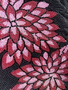 a close up view of a red flower on black fabric with pink flowers in the center