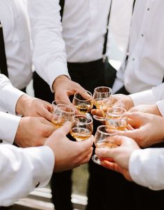 a group of people standing around each other holding wine glasses in their hands and toasting