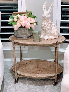 a wooden table topped with flowers and a white rabbit figurine next to it