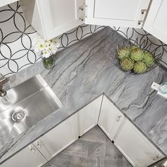 a kitchen with marble counter tops and white cabinets, along with a stainless steel sink