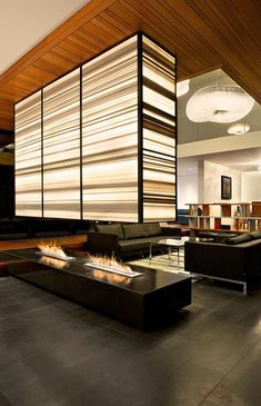 a modern living room with black leather couches and fire pit in the center area