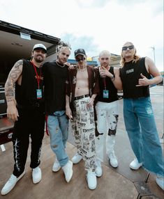 four men standing next to each other in front of a truck