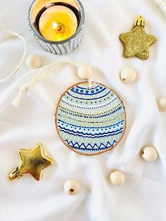 an ornament, candle and other decorations on a white cloth with beads around it