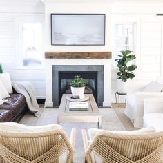 a living room with wicker furniture and a fireplace in the corner, all white