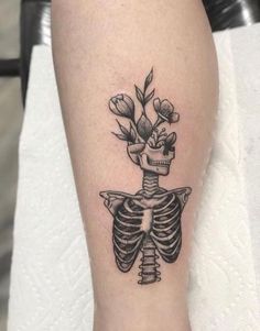 a black and white skeleton tattoo with flowers on it's back leg, showing the ribcage