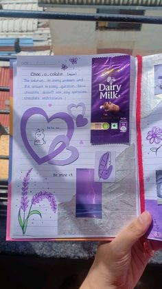 someone is holding up a book with drawings on it and writing down the pages in purple