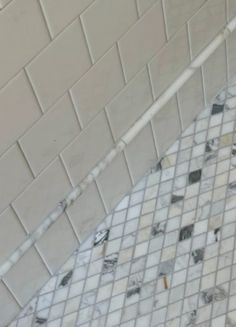 a white toilet sitting in a bathroom next to a tiled wall and floor with black and white tiles on it