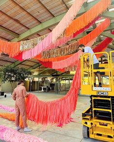 two men working on an orange and pink streamer in the middle of a building