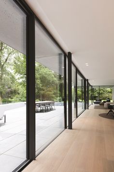 an empty room with wooden floors and glass walls on the outside, looking out onto trees