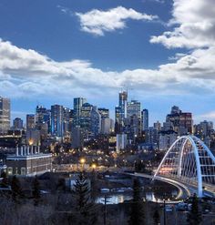 the city skyline is lit up at night, with clouds in the sky above it