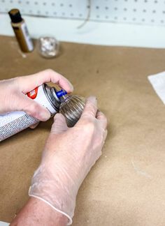 a person is using a spray bottle to apply glue on the paper with their hands