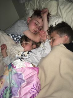 three children are sleeping on a bed together