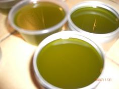 three cups filled with green liquid sitting on top of a tiled floor next to each other