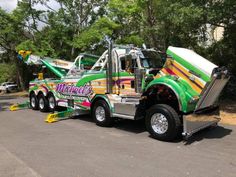 a green and yellow tow truck parked in a parking lot