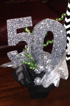 the number 50 is made out of silver glitter and sits in a vase on a table