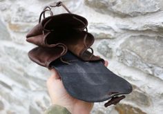 a hand holding an open purse in front of a stone wall