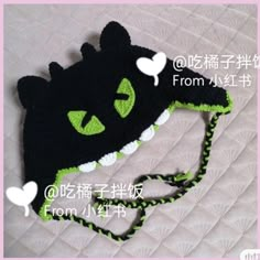 a crocheted black cat hat with green eyes on it's brim