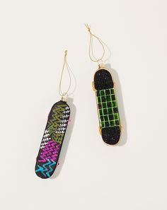 two skateboards are hanging from gold chains on a white surface, one is green and the other is black