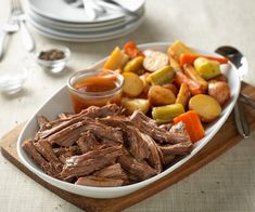 a white plate topped with meat and veggies on top of a wooden cutting board