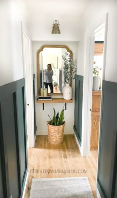 a woman standing in the doorway of a house looking at herself in the bathroom mirror