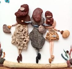 a group of people made out of rocks and pebbles on a white surface with plants