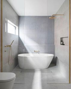 a white bath tub sitting in a bathroom next to a shower head and faucet