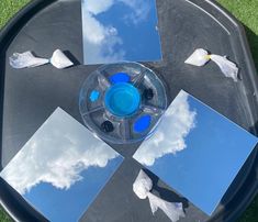 several mirrors are arranged on a table with blue sky and clouds in the background,