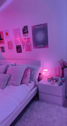 a bed room with a neatly made bed and pink lighting