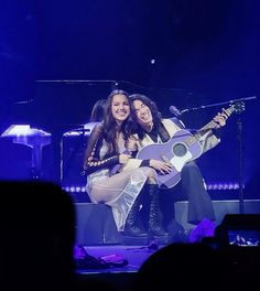 two women on stage playing guitar and singing