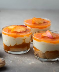 three desserts in small glass dishes sitting on a table next to nuts and other food