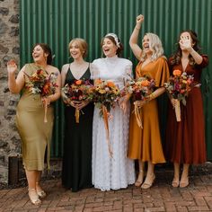 a group of women standing next to each other in front of a green metal wall