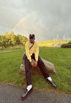 a man sitting on top of a rock in the grass