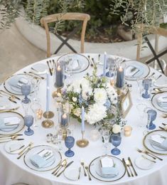 a white table topped with blue and gold place settings