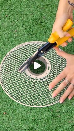 a person is using scissors to cut through the hole in the grass on top of a lawn