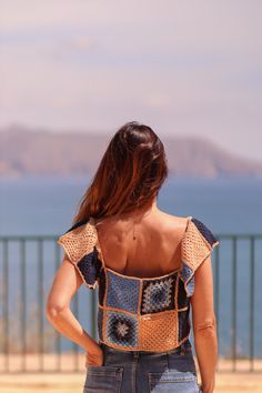 a woman with her back to the camera looking out at the ocean and mountains in the distance