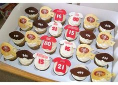 cupcakes decorated with football jersey and numbers are displayed in a box on the table