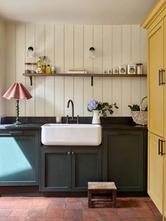 a kitchen with green cabinets and white sink in the center, along with yellow cupboards